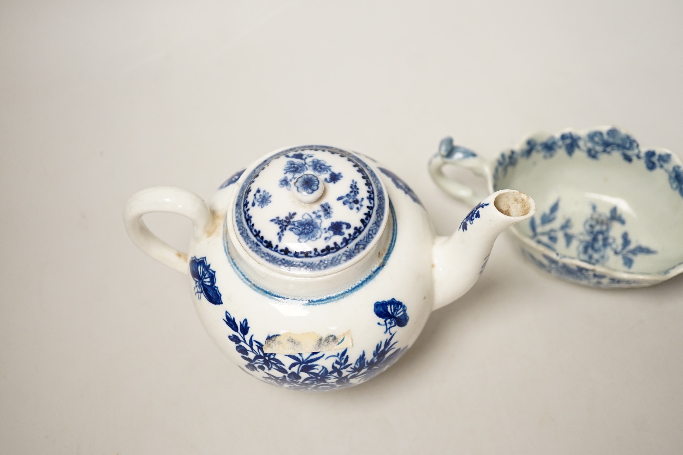 A Liverpool porcelain blue and white sauceboat and a Worcester teapot. Tallest 12cm